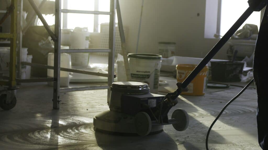 Builder polishing mortar floor at construction site of new appartments. Mechanized grout screed