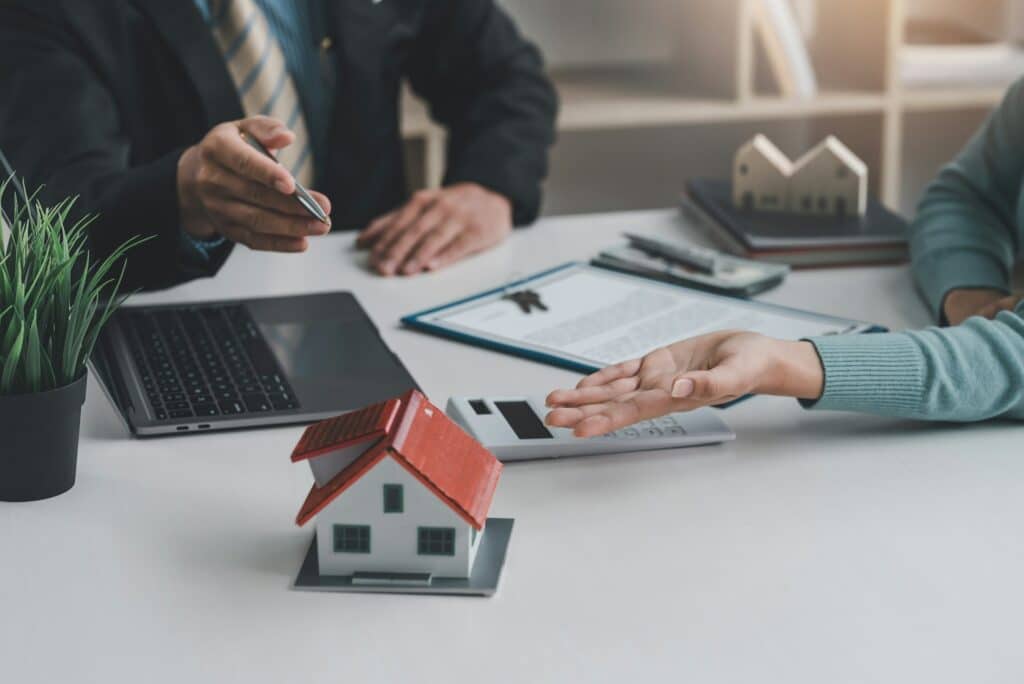 Real estate agents discuss the terms of the contract for the sale of the house at the office.